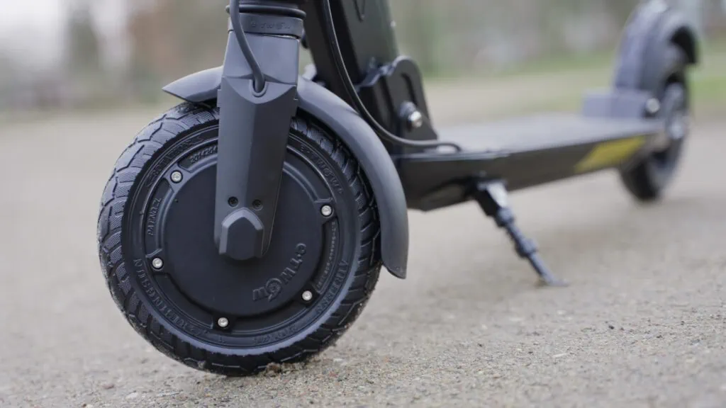 Fluid Mosquito Review: Smaller, Faster, Better? 33 Close-up of the Fluid Mosquito electric scooter's front wheel and motor, highlighting the tread pattern on a textured pavement