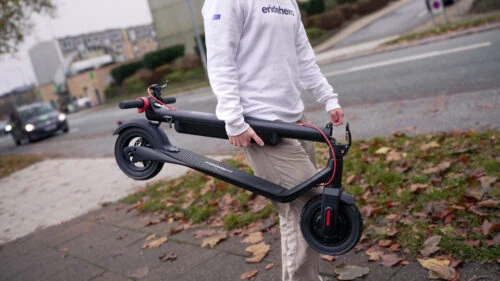 Rasmus from ERideHero carrying a folded electric scooter with one hand